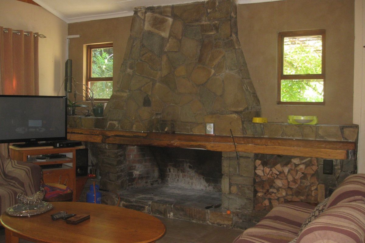 A cozy living room featuring a prominent floor-to-ceiling stone fireplace with a timber mantelpiece and integrated firewood storage.