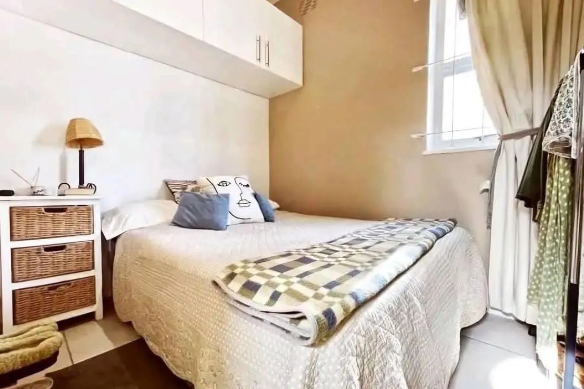 A compact bedroom featuring built-in overhead cabinetry and tiled flooring, providing functional storage space within the apartment.
