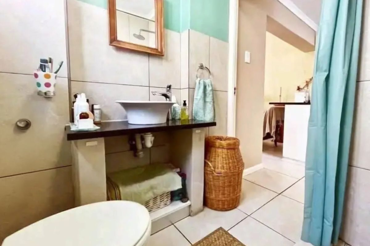 A functional bathroom featuring a vessel sink vanity, tiled walls, and a shower area with a curtain.