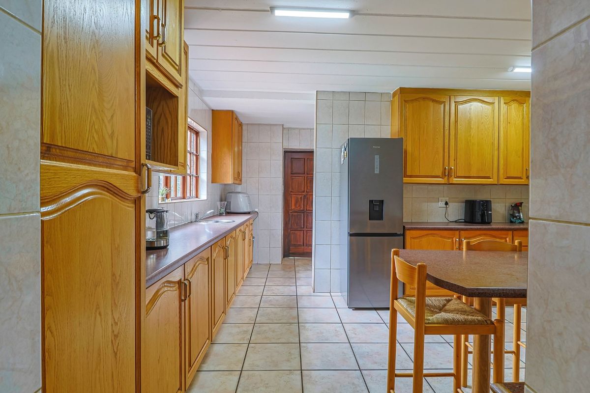 A functional kitchen featuring traditional timber cabinetry, tiled flooring, and wall tiling, providing a practical workspace with integrated storage and preparation areas.