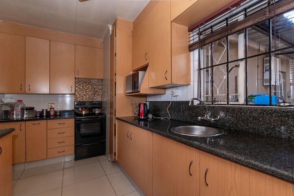 Functional kitchen featuring light wood cabinetry, granite countertops, stainless steel sink, and a built-in oven with a mosaic tile backsplash.