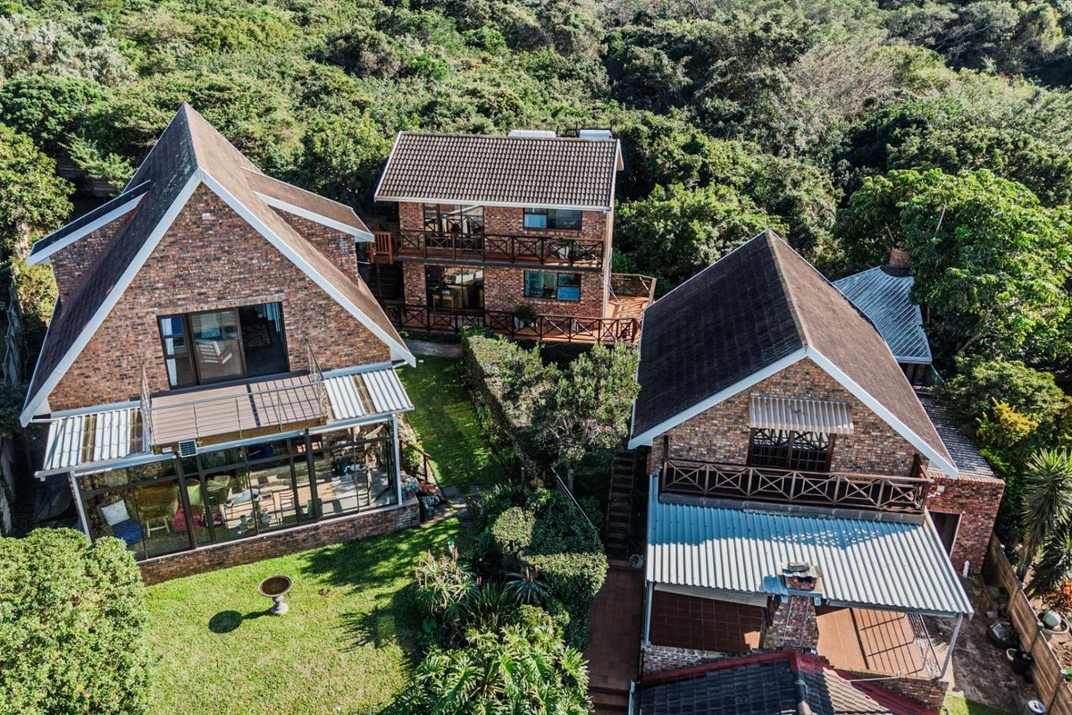 Aerial view of a multi-structure residential property featuring brick facades, tiled roofs, balconies, and a well-maintained garden setting.