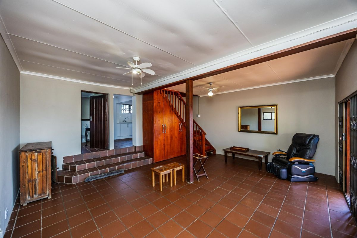 Spacious living area featuring tiled flooring, built-in wooden cabinetry, and a staircase leading to the upper level.