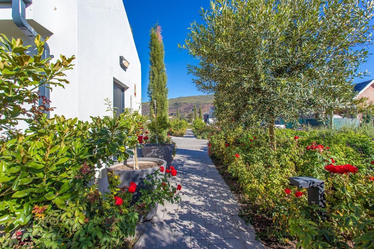 A well-maintained garden pathway alongside the exterior wall of the residence, featuring paved walkways and established landscaping.