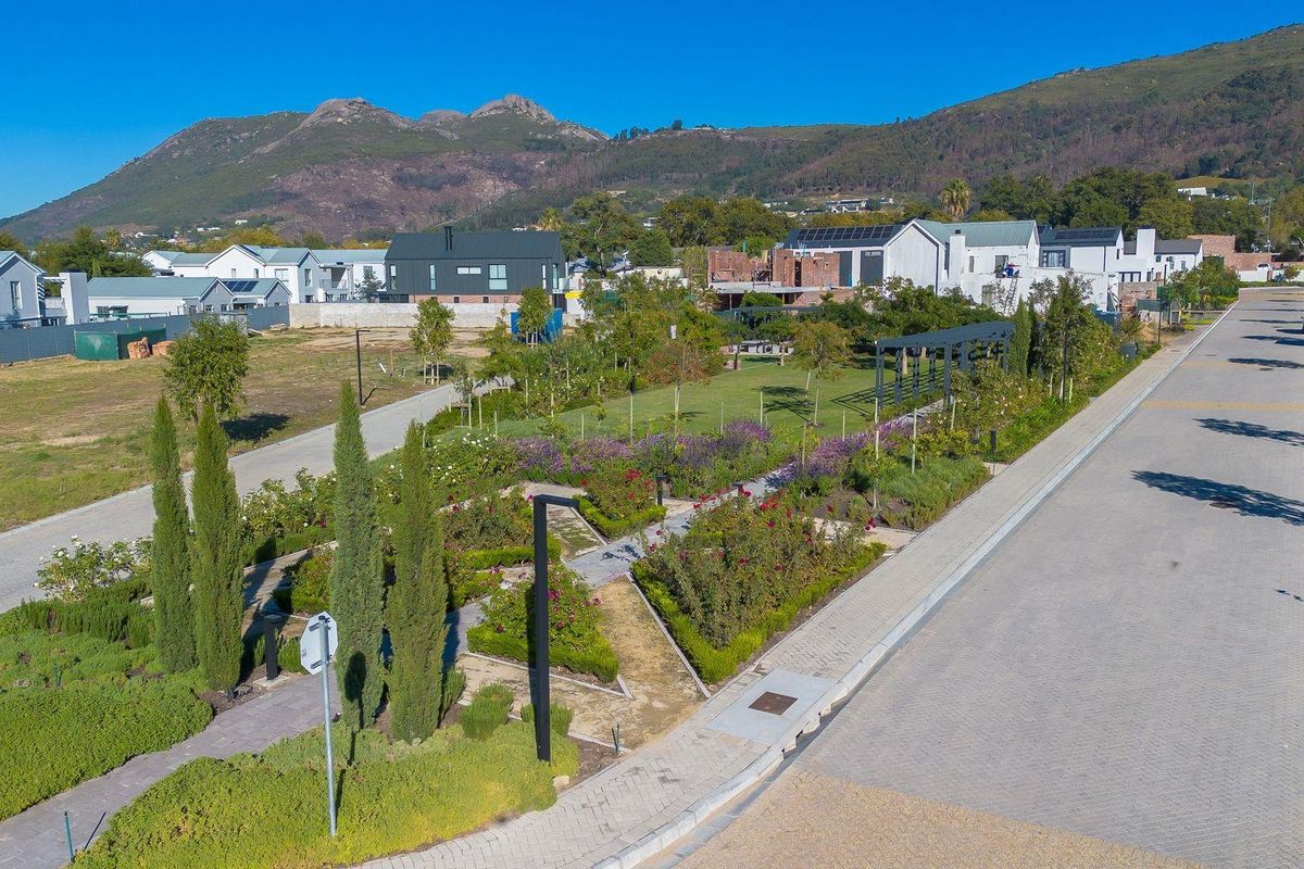 Aerial view of a landscaped residential estate park featuring manicured gardens, paved walkways, and surrounding modern residential properties.