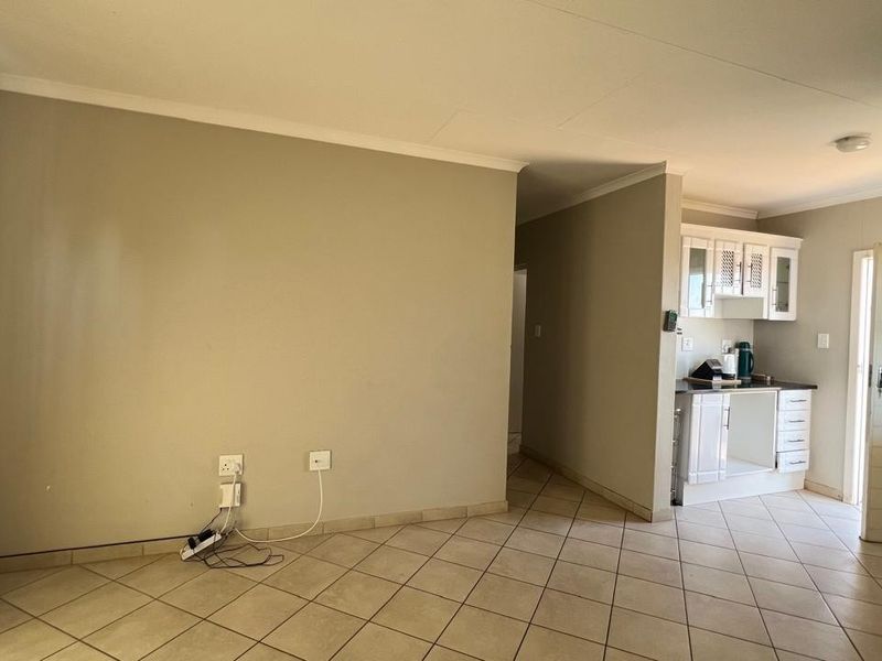 Open plan living area featuring tiled flooring and a compact kitchen with white cabinetry, providing a functional layout for daily living.
