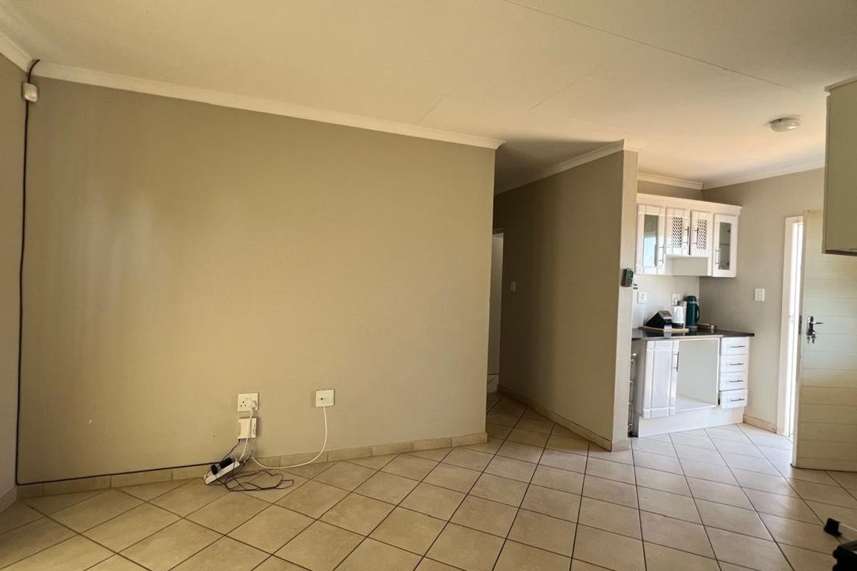 Open plan living area featuring tiled flooring and a compact kitchen with white cabinetry, providing a functional layout for daily living.
