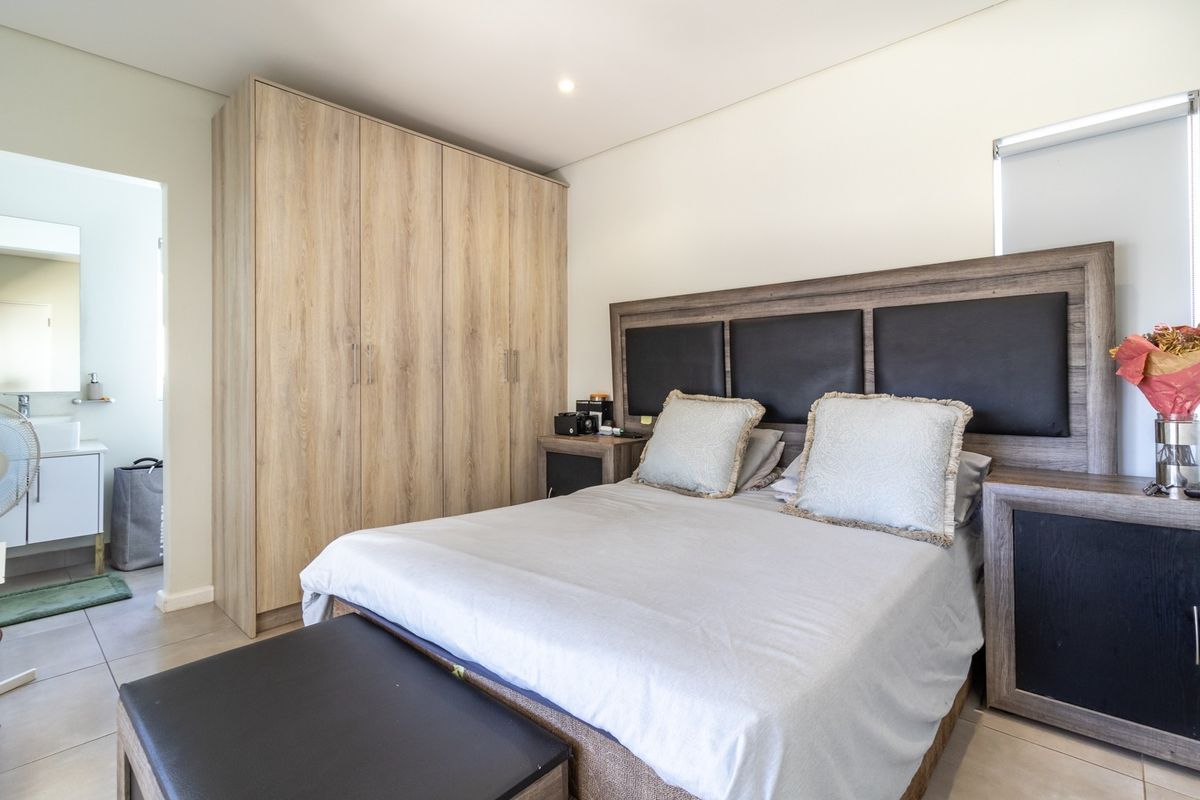 A well-maintained bedroom featuring built-in wooden cabinetry and an en-suite bathroom with modern fixtures.