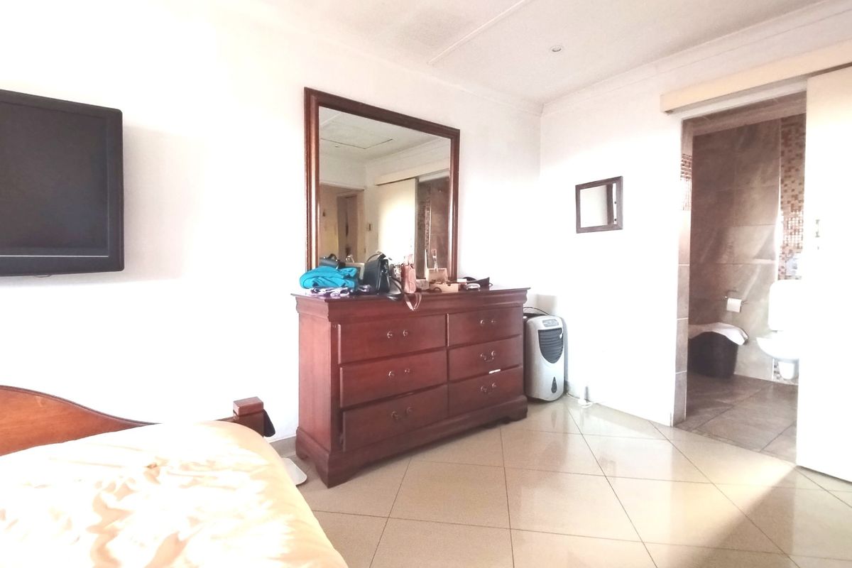 A bedroom featuring tiled flooring and an en-suite bathroom, providing a functional and well-lit living space.