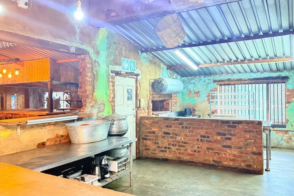 Rustic kitchen area featuring exposed brick walls, corrugated metal roofing, and a brick service counter, requiring significant cosmetic renovation and finish upgrades.