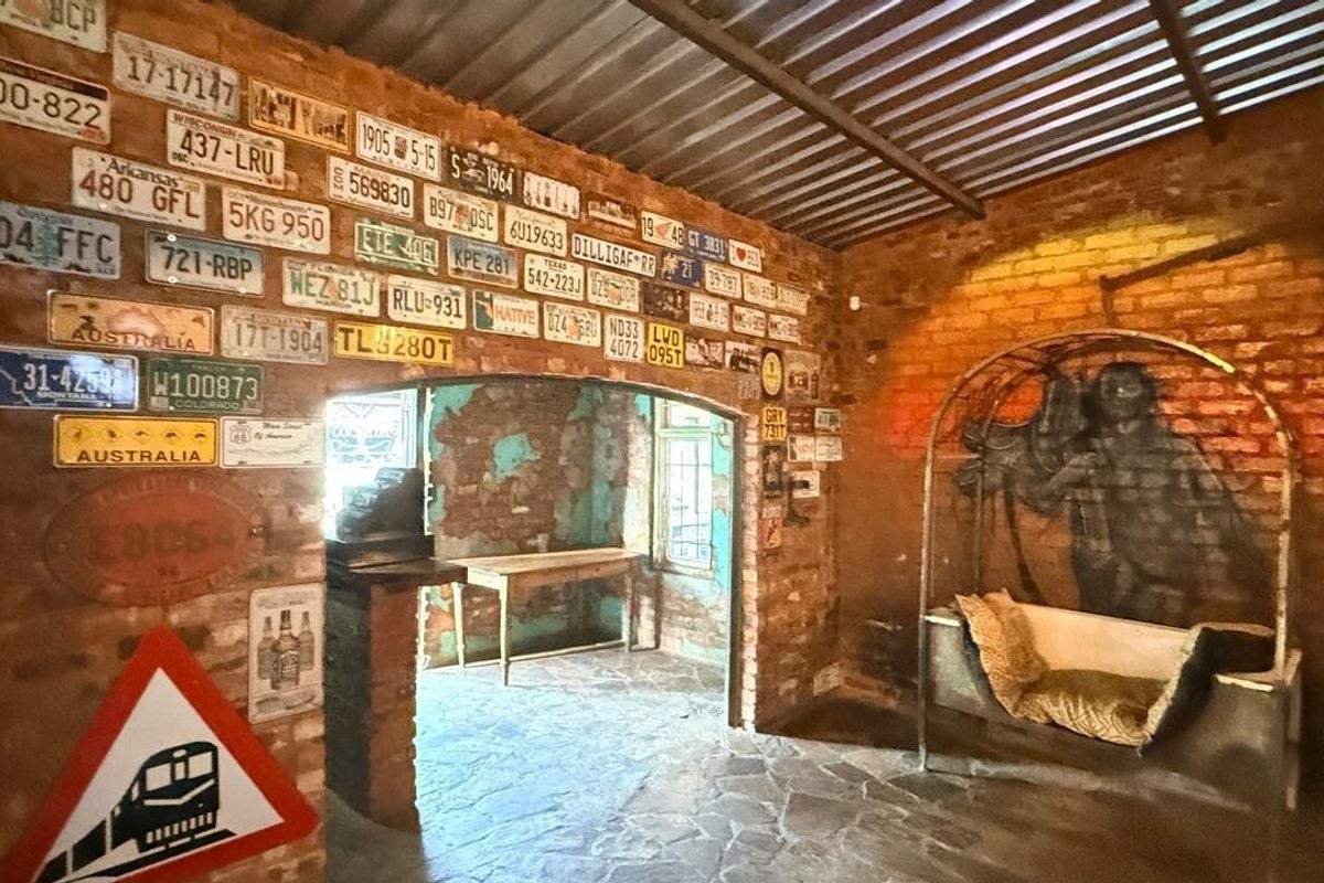 A rustic living area featuring exposed brick walls, stone flooring, and a corrugated metal ceiling, creating a unique industrial-style atmosphere.