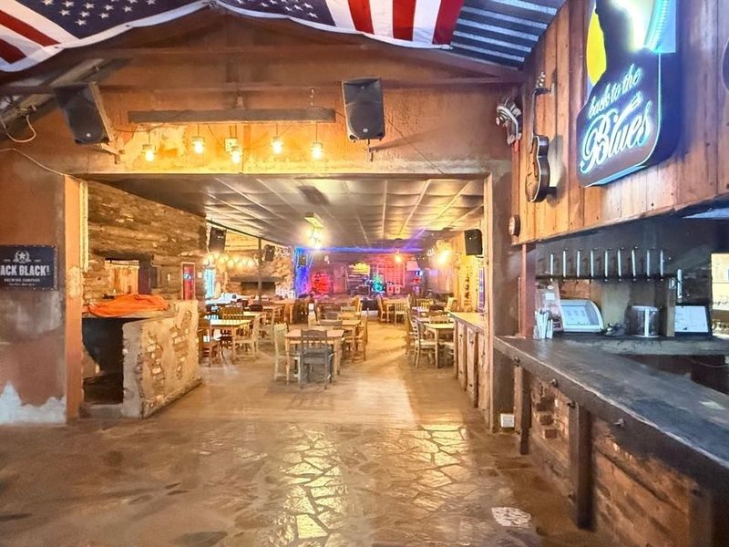 Spacious rustic bar area featuring exposed timber beams, stone flooring, and a built-in bar counter, suitable for entertainment or hospitality use.