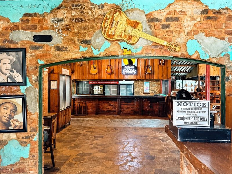 Rustic bar area featuring exposed brick walls with distressed plaster, stone flooring, and a built-in timber bar counter.
