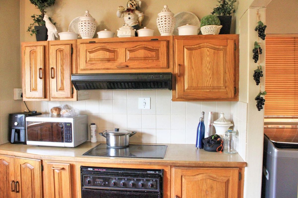 A functional kitchen featuring traditional wooden cabinetry, a ceramic tile backsplash, and integrated cooking appliances including an electric hob and oven.