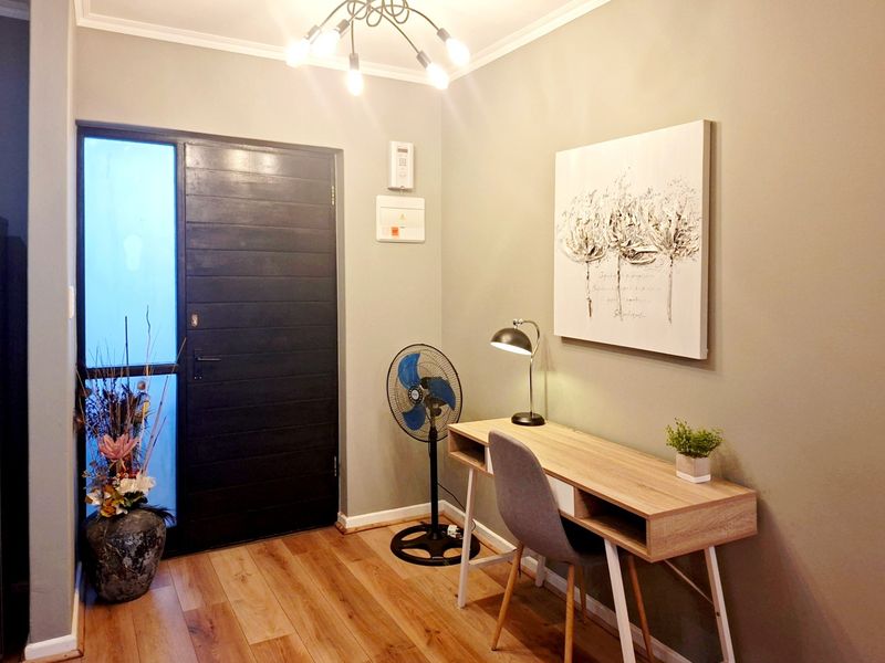 A welcoming entrance hall featuring timber-look flooring, a solid timber front door with side light, and modern lighting fixtures.
