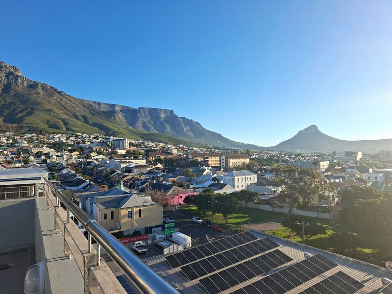 Elevated panoramic view overlooking the surrounding residential neighborhood and mountain range, featuring a modern stainless steel balustrade in the foreground.