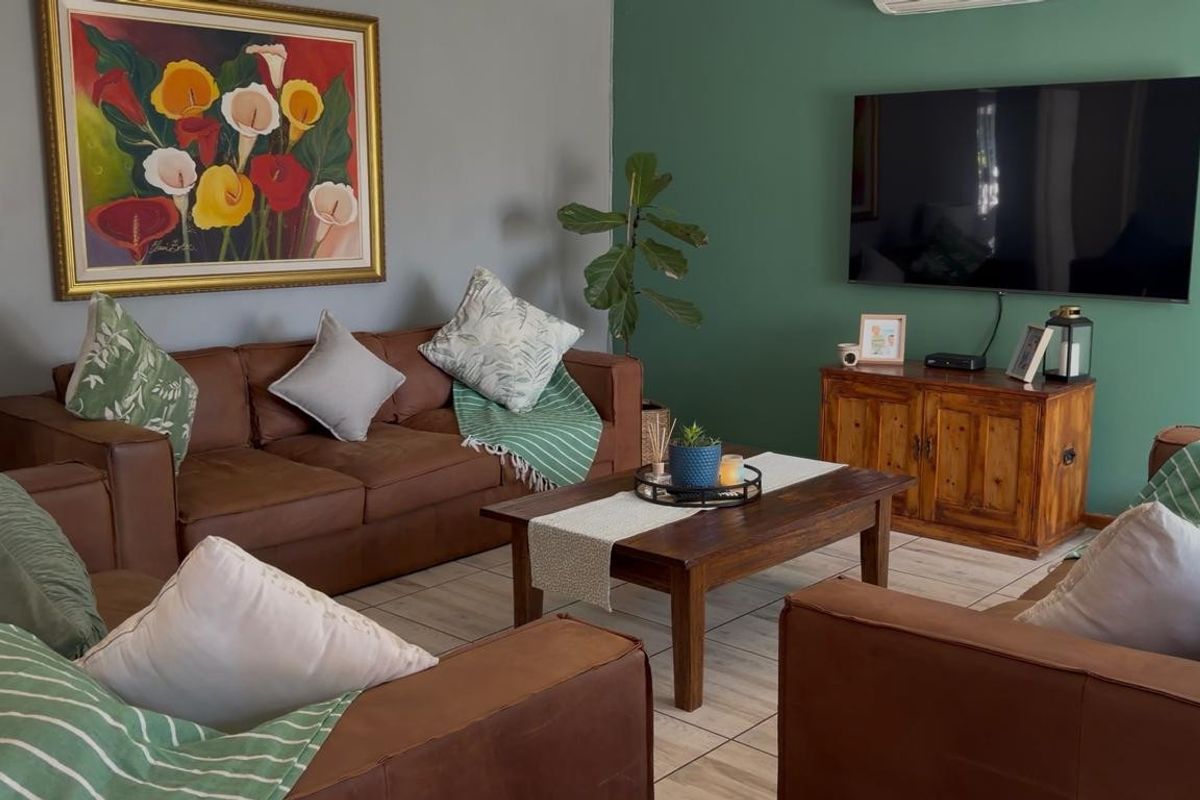 A comfortable living room featuring tiled flooring and a wall-mounted air conditioning unit, finished with a dual-tone painted wall scheme.