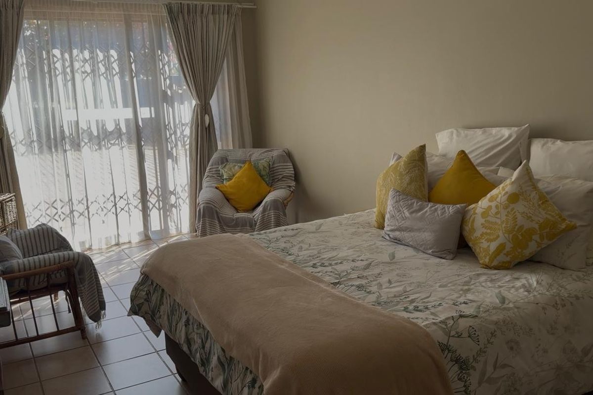 A bedroom featuring tiled flooring and a sliding glass door with an integrated security gate, providing access to the exterior.