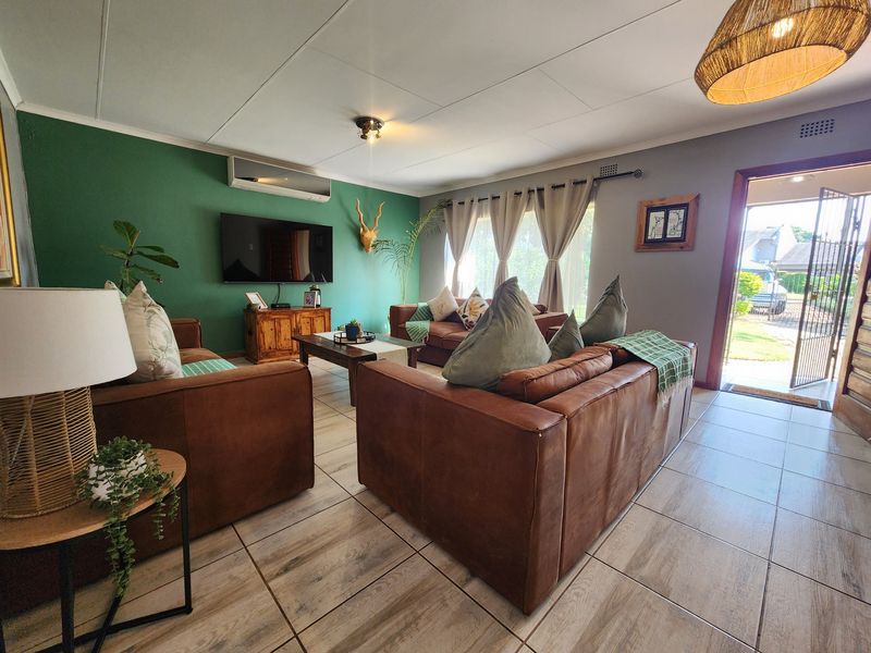 A comfortable living room featuring ceramic floor tiles, a split-system air conditioner, and direct access to the exterior through a security gate.