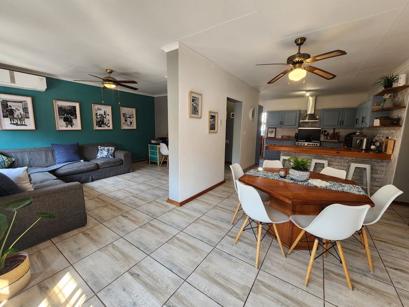 Open-plan living and dining area featuring tiled floors, ceiling fans, and a functional kitchen with breakfast bar and modern cabinetry.