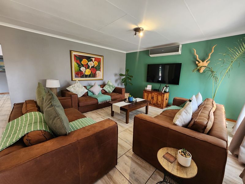 A comfortable living room featuring tiled flooring, a split-system air conditioner, and a feature wall, providing a functional and inviting space.