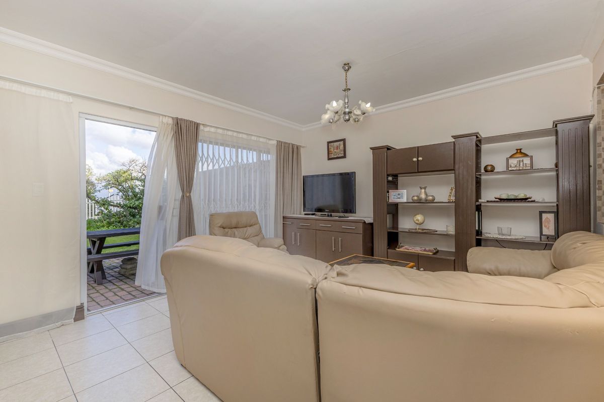 A comfortable living room featuring tiled flooring, a decorative chandelier, and a sliding glass door providing direct access to the outdoor patio area.