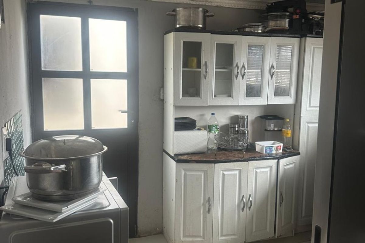 A compact kitchen area featuring white cabinetry, tiled flooring, and direct access to an exterior door.