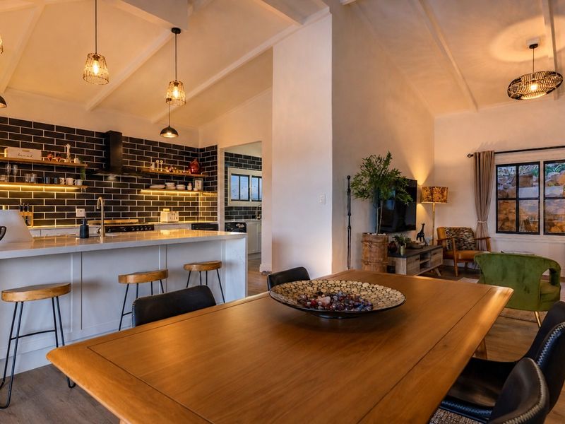 Spacious open-plan living area featuring a modern kitchen with a large island, subway tile backsplash, and vaulted ceilings with exposed beams.