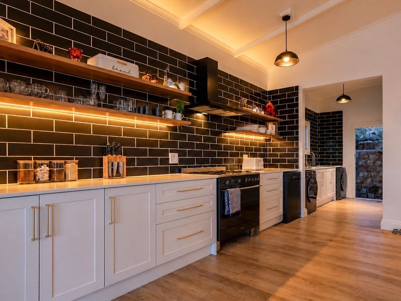 Modern kitchen featuring sleek white shaker cabinetry, black subway tile backsplash, floating timber shelving with integrated lighting, and a professional-style gas range.