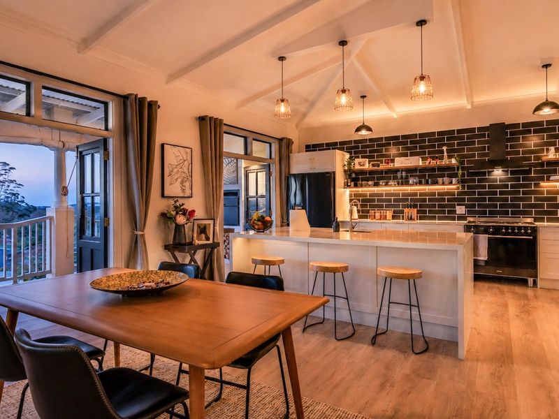 Spacious open-plan kitchen and dining area featuring a large island, modern subway tile backsplash, and direct access to a covered balcony with scenic views.