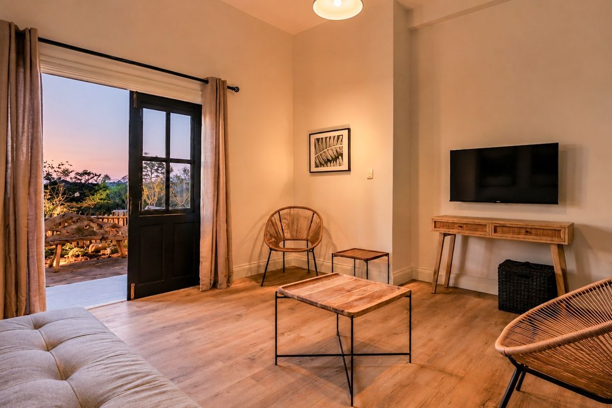 A bright living room featuring light wood-look laminate flooring and a classic black-framed french door providing direct access to an outdoor patio area.