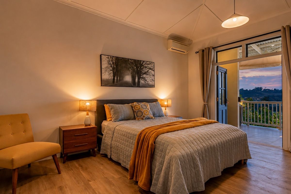A well-appointed bedroom featuring timber flooring, an air conditioning unit, and direct access to a private balcony with scenic views.