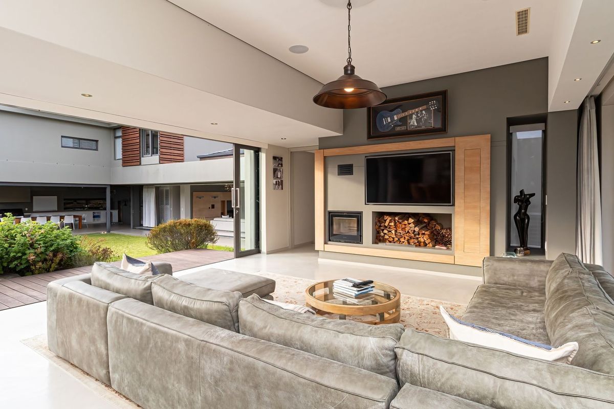Modern living room featuring a built-in fireplace, integrated media unit, and large sliding glass doors that open onto a landscaped courtyard.