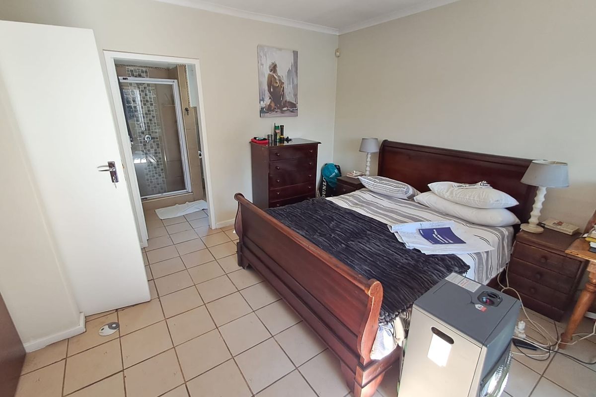 A bedroom featuring tiled flooring and an en-suite bathroom with a glass-enclosed shower.