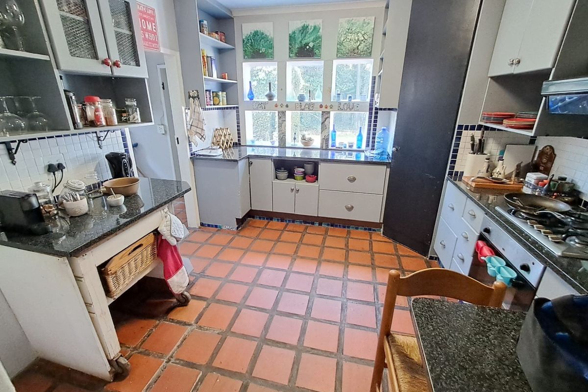 A functional kitchen featuring granite countertops, tiled flooring, built-in cabinetry, and a gas cooktop with an integrated extractor fan.