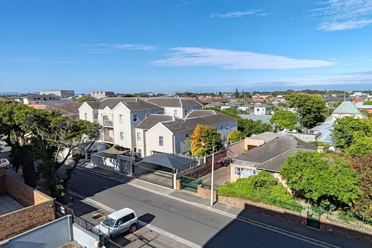 Elevated aerial view overlooking the surrounding residential neighborhood, showcasing the street layout, nearby apartment complexes, and established greenery.