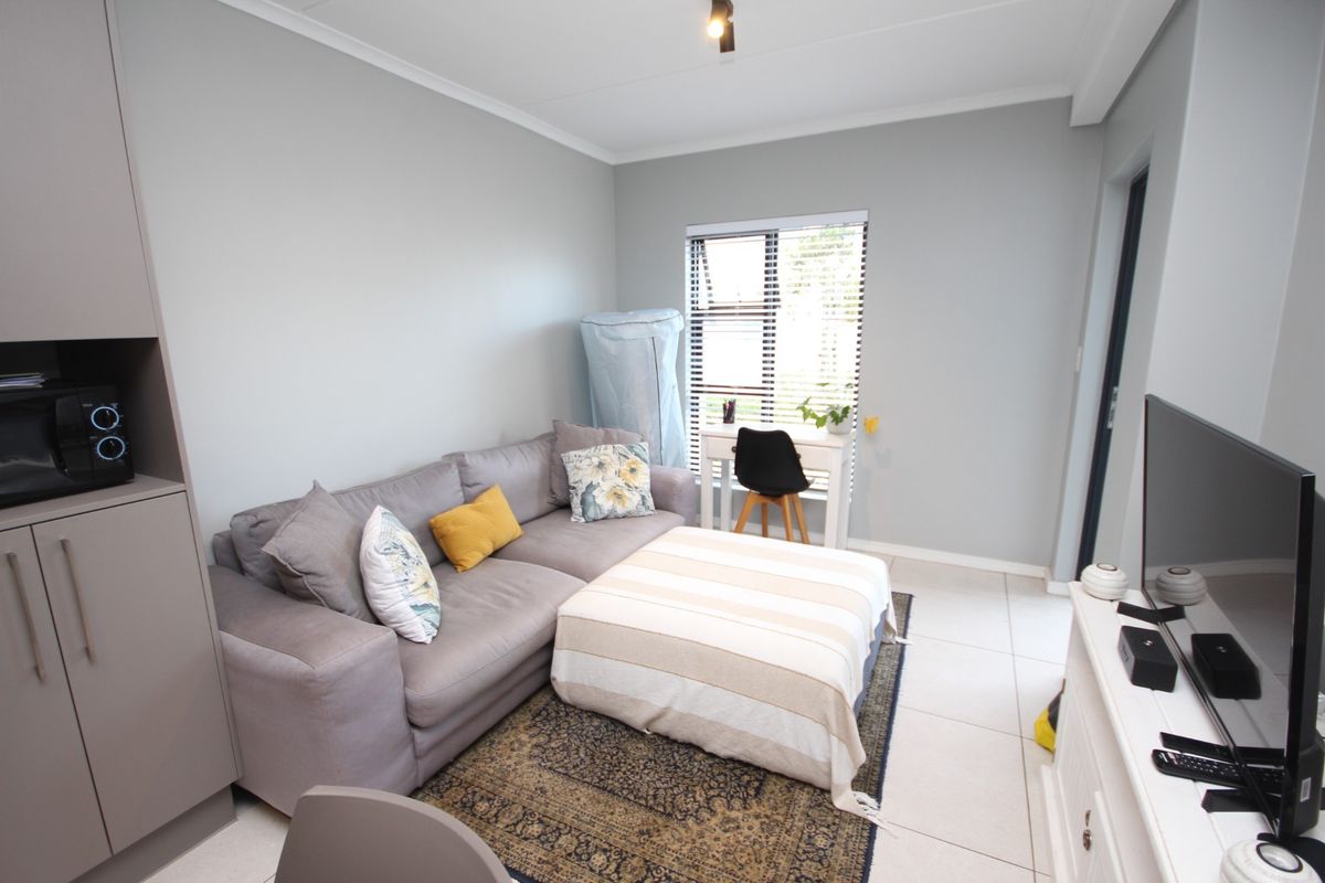 A well-maintained living room featuring neutral wall tones, tiled flooring, and a built-in storage cabinet, offering a functional and comfortable living space.