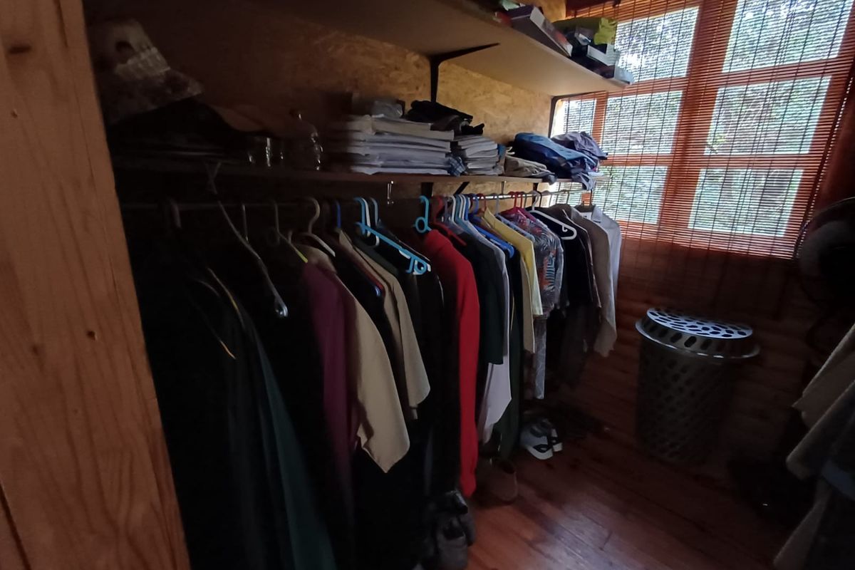 A functional walk-in closet or storage area featuring wooden wall paneling, timber flooring, and built-in shelving units.