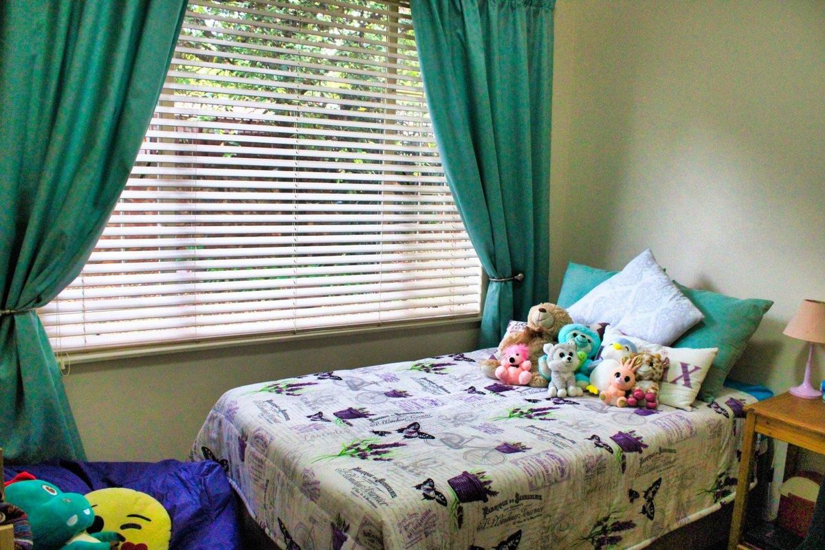 A bedroom featuring a window with venetian blinds and curtain rods, providing natural light and a functional space.