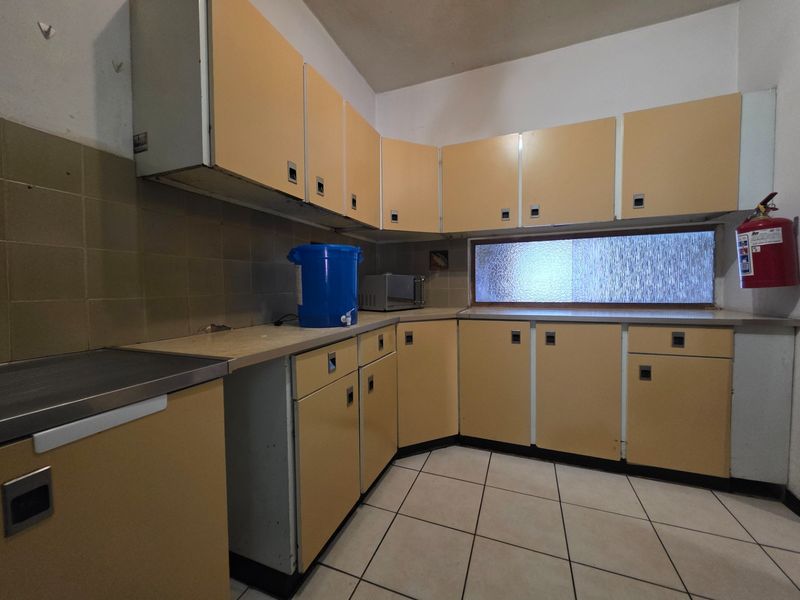 A dated kitchen featuring original cabinetry, tiled flooring, and a tiled backsplash, offering a functional layout ready for modernization and renovation.
