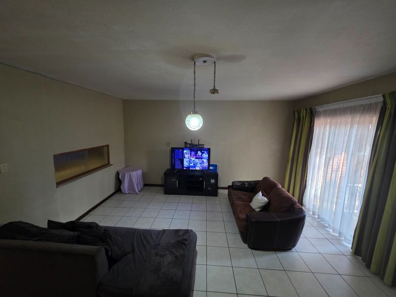 A spacious living room featuring tiled flooring, a built-in wall niche, and large sliding glass doors providing access to the outdoor area.