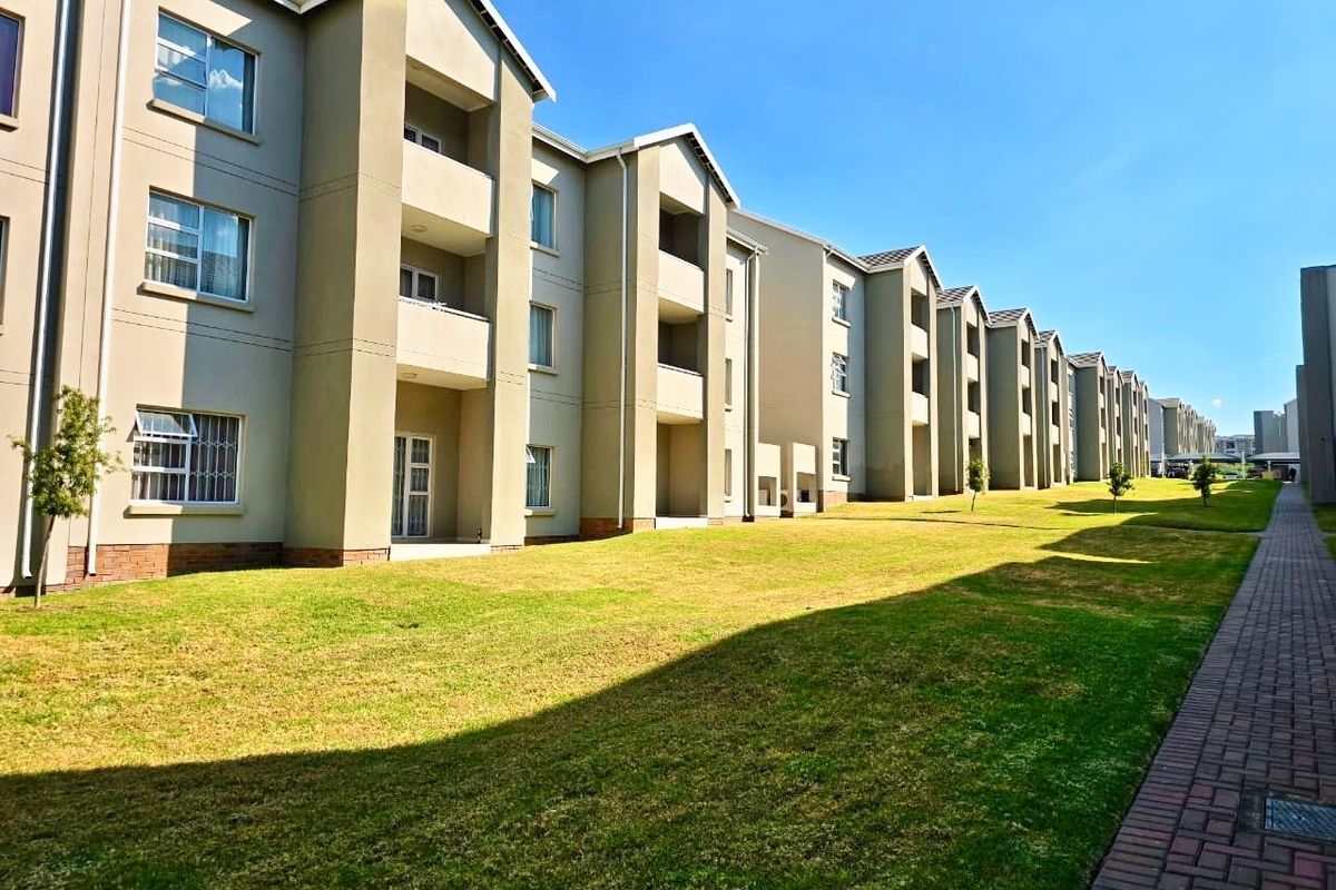 A view of the apartment complex exterior, featuring multi-story residential blocks with balconies, paved walkways, and well-maintained communal lawn areas.