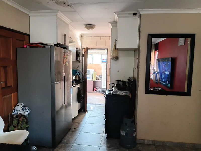 A compact kitchen area featuring tiled flooring, built-in cabinetry, and a gas stove, showing signs of wear and ceiling water damage.