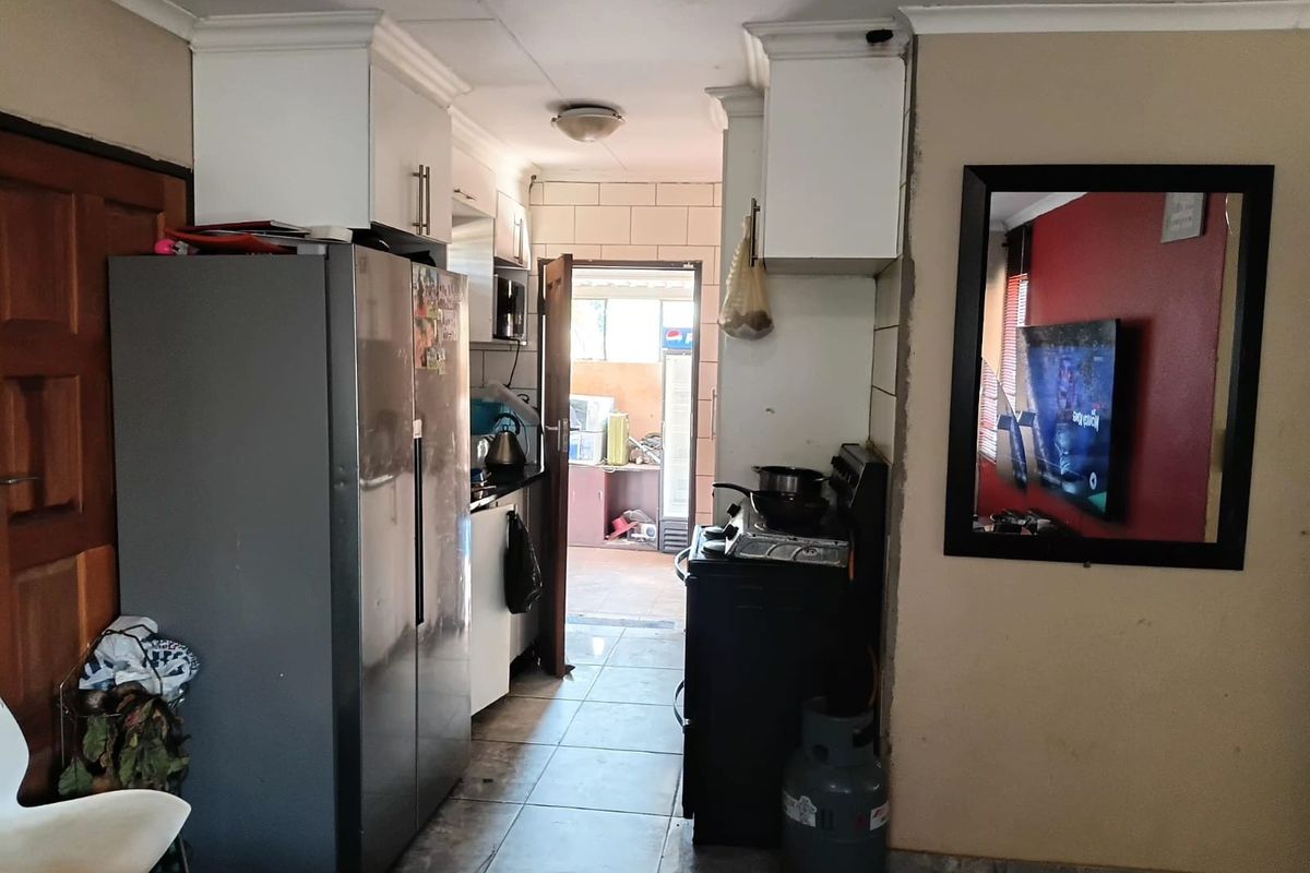 A compact kitchen area featuring tiled flooring, built-in cabinetry, and a gas stove, showing signs of wear and ceiling water damage.