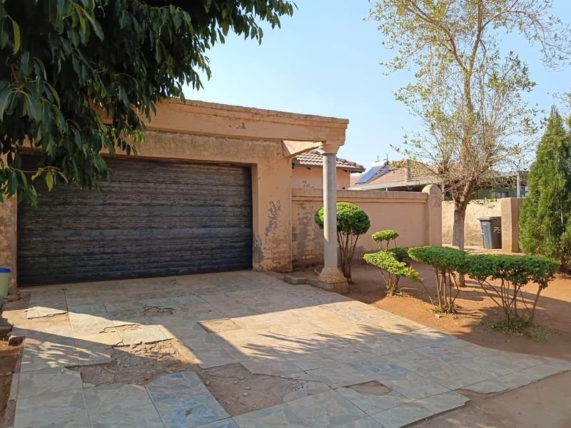 Exterior view of a single garage featuring a roll-up door, a decorative column, and a driveway with significant tile damage requiring repair.