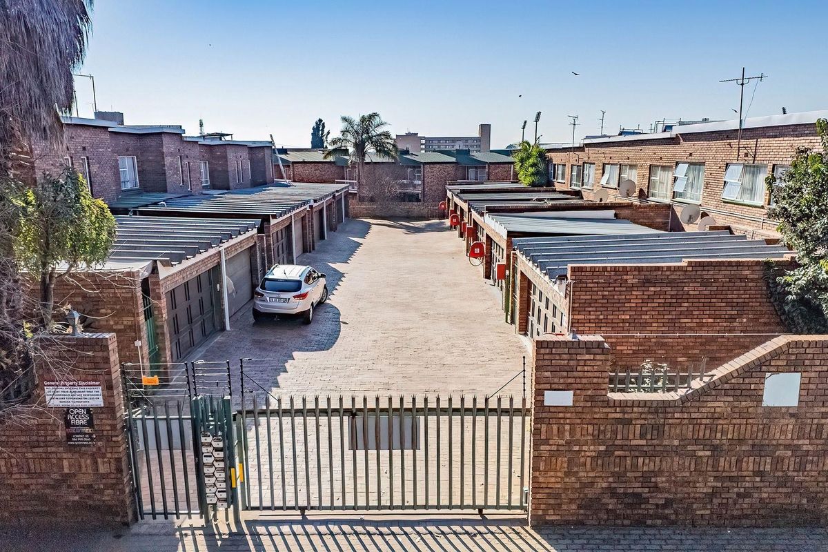 An elevated view of a secure residential apartment complex courtyard featuring multiple brick-built garages and paved driveway access.