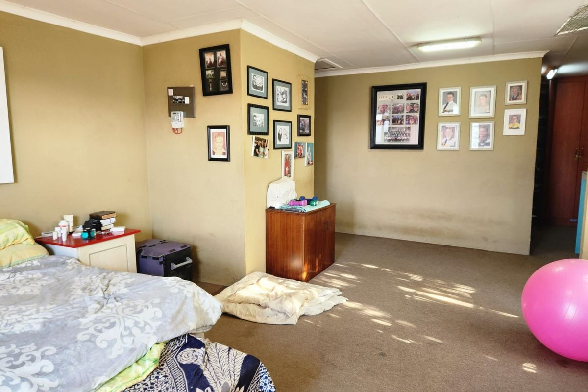 A spacious bedroom featuring neutral wall tones, carpeted flooring, and built-in electrical infrastructure, offering a blank canvas for potential interior updates.