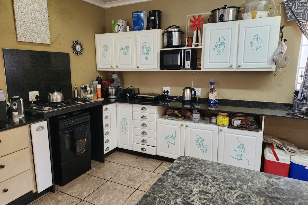 A functional kitchen featuring granite countertops, built-in cabinetry, and a gas hob with an integrated oven, finished with ceramic floor tiles.