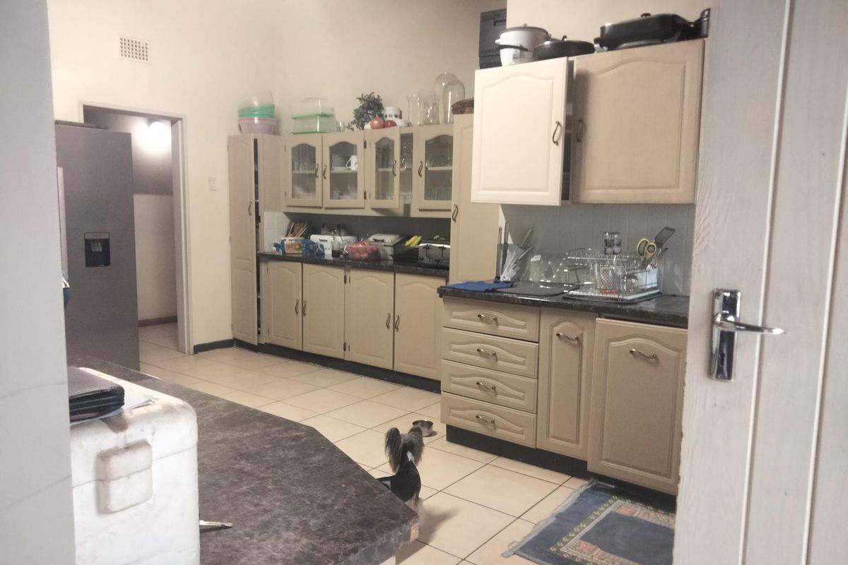 A functional kitchen featuring traditional cabinetry, laminate countertops, and tiled flooring, offering ample storage and workspace for daily meal preparation.