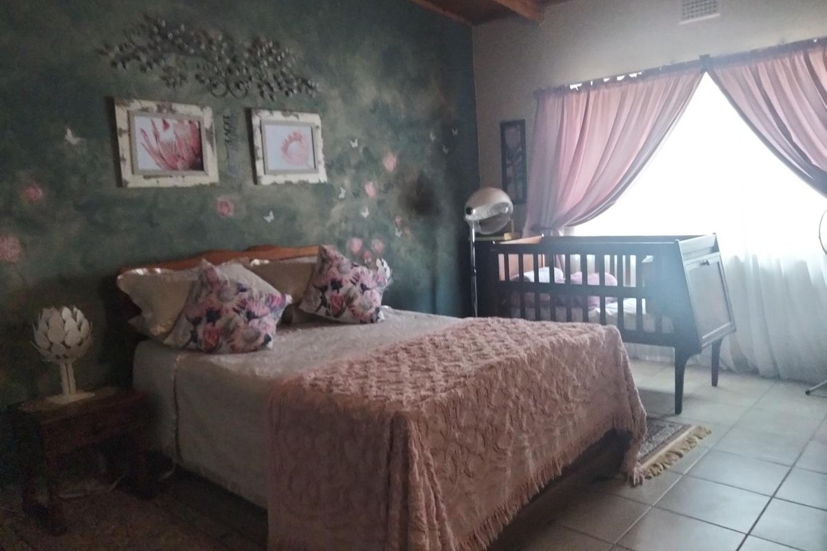 A bedroom featuring tiled flooring, exposed wooden ceiling beams, and a decorative painted feature wall.